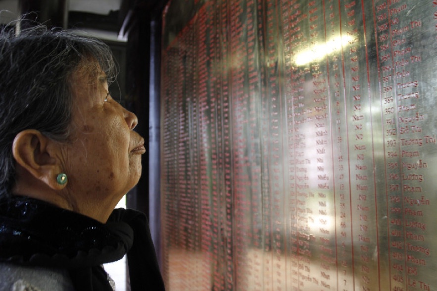 Nesta foto tirada em 15 de março de 2018, o morador local Truong Thi Hong, 76 anos, observa os nomes de parentes mortos durante o massacre de My Lai no museu do memorial da guerra em Son My village, província de Quang Ngai. NHAC NGUYEN / AFP / GETTY IMAGES