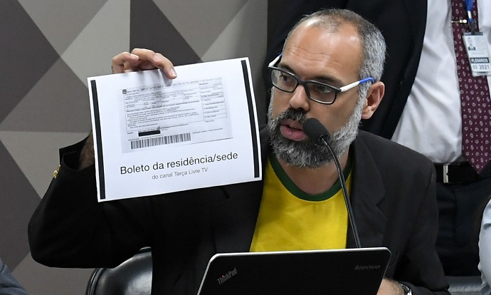 O blogueiro Allan dos Santos, do Terça Livre, participa de audiência no Senado Federal vestindo uma camiseta com as cores da bandeira do Brasil e um terno