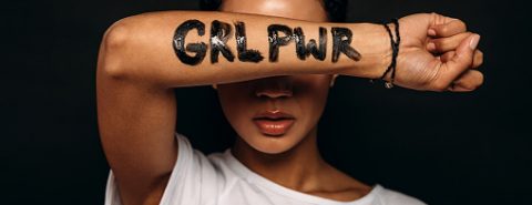 Mulher negra mostra braço com a mensagem "girl power" em tinta preta