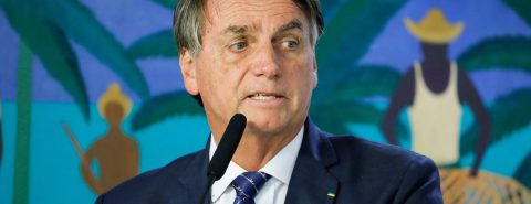 Jair Bolsonaro de terno azul marinho e broche verde no paletó