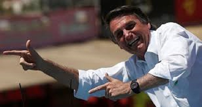 Sorridente, ex-presidente Jair Bolsonaro faz arminha com as mãos