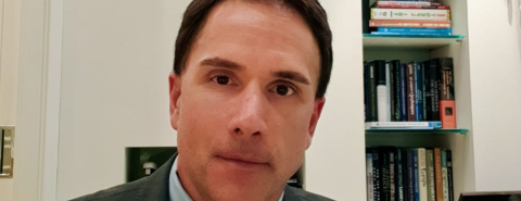 Juiz Eduardo Appio, homem branco com terno e gravata, expressão séria e estante de livros no fundo da sala