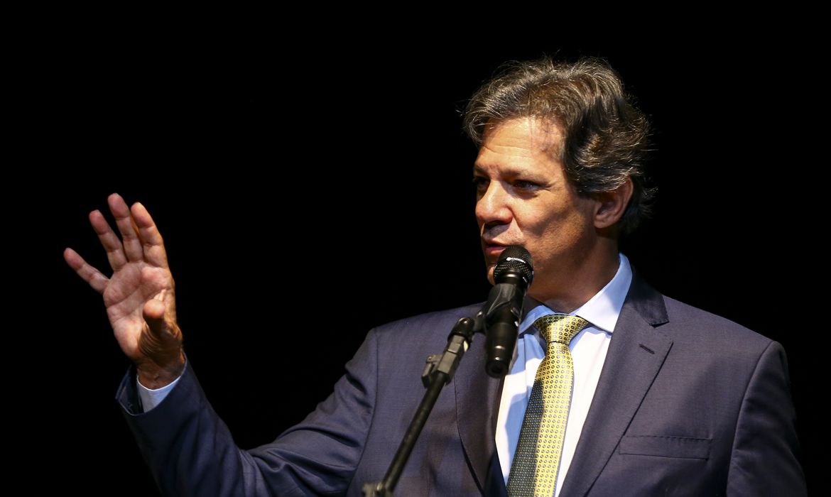Fernando Haddad de paletó escuro e gravata amarela
