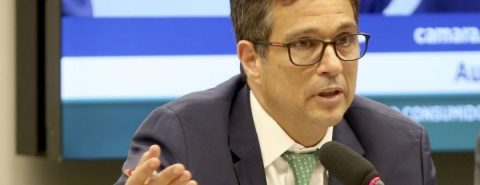 Roberto Campos Neto, presidente do Banco Central. Homem branco, usa óculos, terno escuro, camisa branca e gravata verde