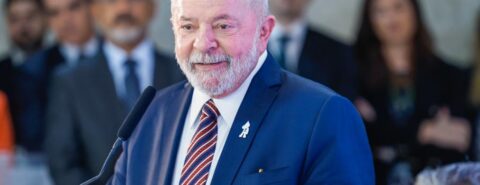 Lula usa terno azul e gravata listrada, com tons de vermelho e azul marinho, enquanto fala na tribuna Palácio do Planalto