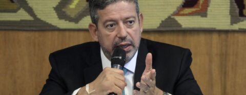 Homem branco de terno segura microfone