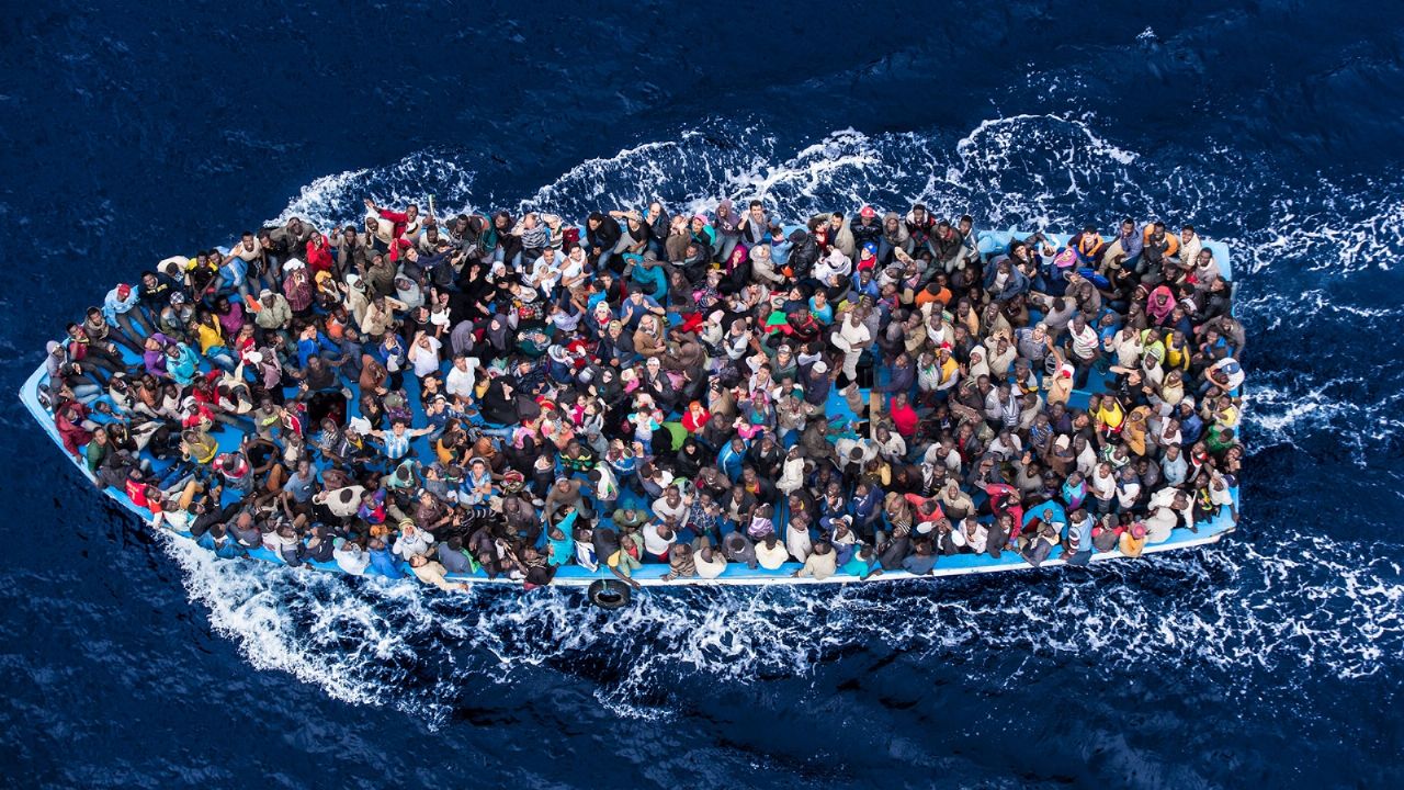 Migrantes lotam uma embarcação na travessia do Mar Mediterrâneo
