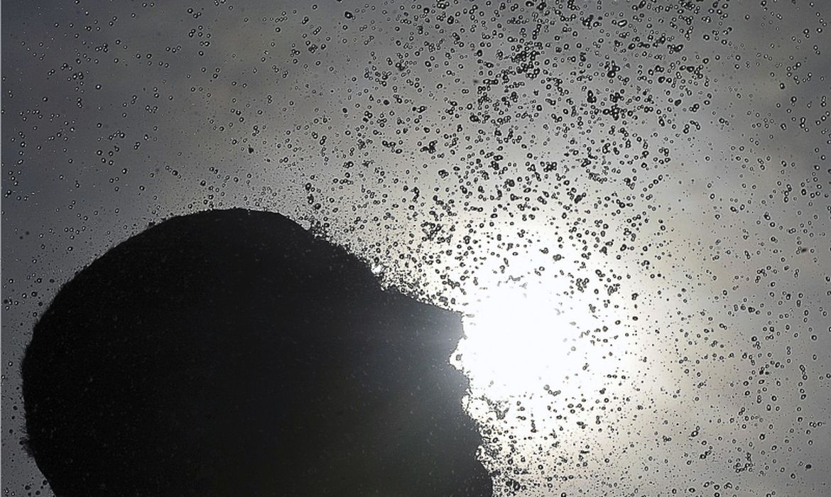 Uma pessoa ao sol jogando água em seu rosto