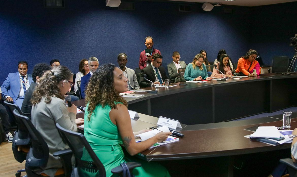 Grupo técnico reunido em uma mesa são fotografados enquanto apresentam o relatório