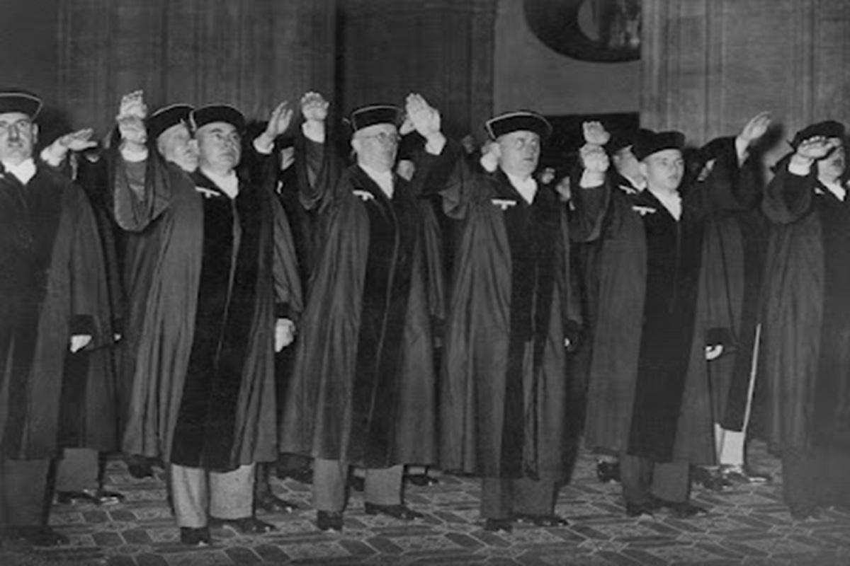 GERMANY: JUDGES, 1936. 
Ceremony in criminal court at Berlin, Germany with judges displaying their loyalty to the Nazi Party; party insignia are prominent on their robes. Photograph, 1 October 1936. Full Credit: Ullstein Bild / Granger. All Rights Reserved.
