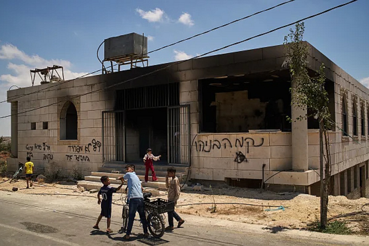 Crianças em frente a uma mesquita incendiada em ataque terrorista de colonos israelenses na vila de Qusra na Cisjordânia, julho 2026 \ Foto: Leo Correa / AP - Reprodução